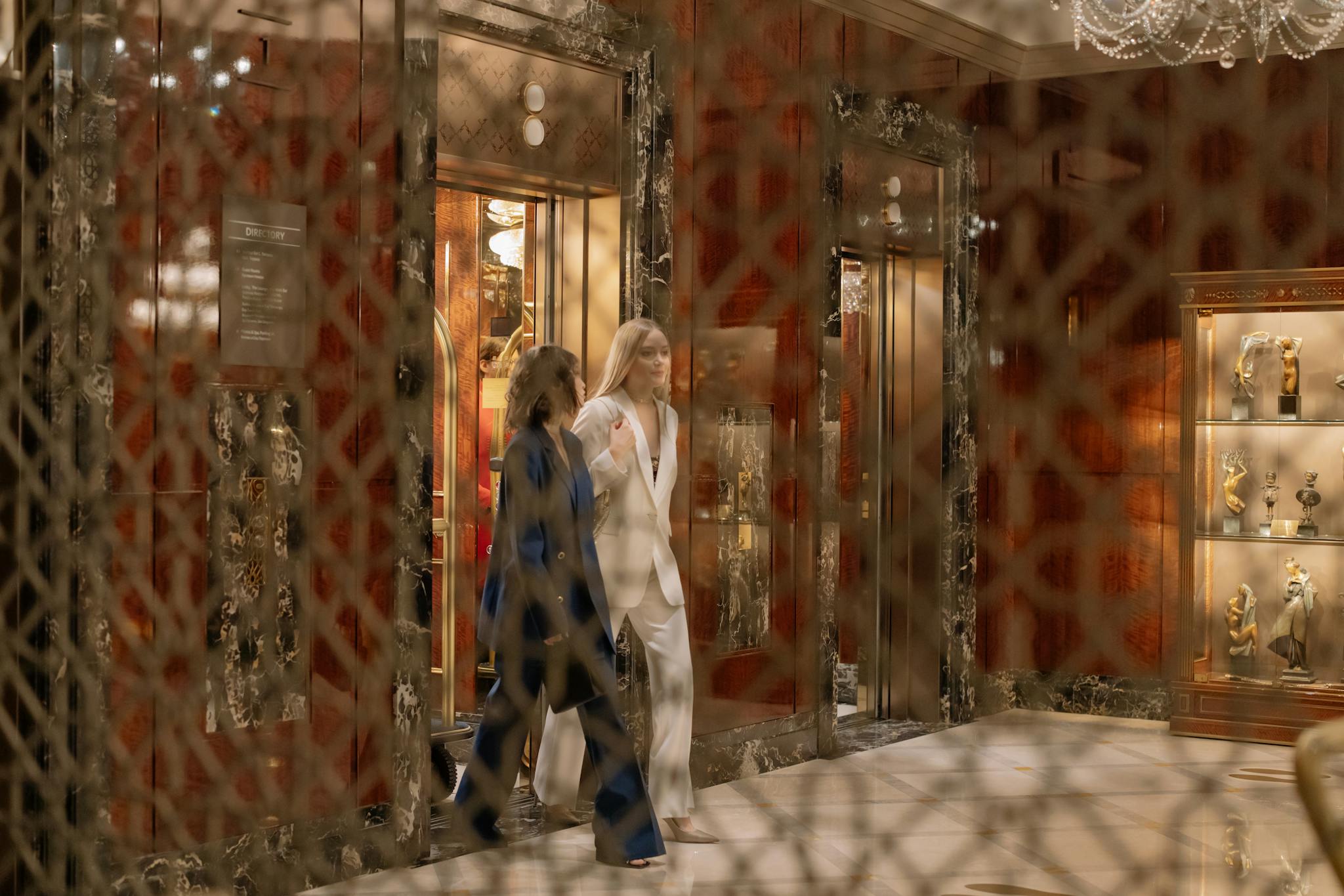 Luxurious hotel interior with two women elegantly dressed exiting an elevator in a stylish hall.